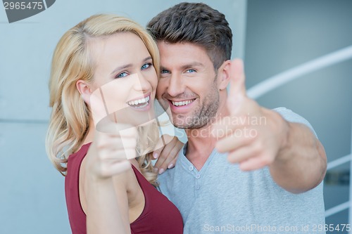 Image of Happy laughing couple giving a thumbs up