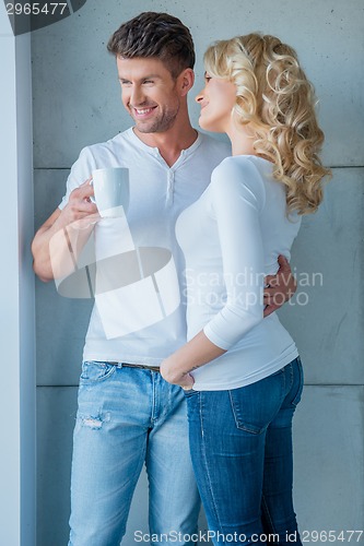 Image of Affection couple standing looking out of a window