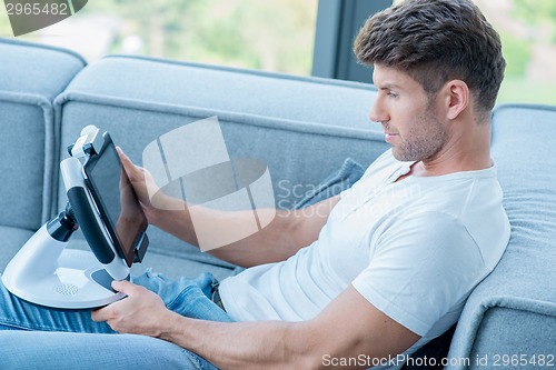 Image of Young Handsome Man on Couch Playing His Gadget