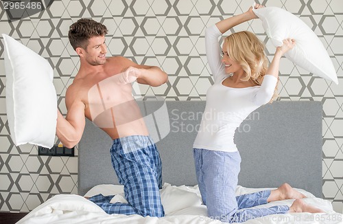 Image of Playful couple having a pillow fight