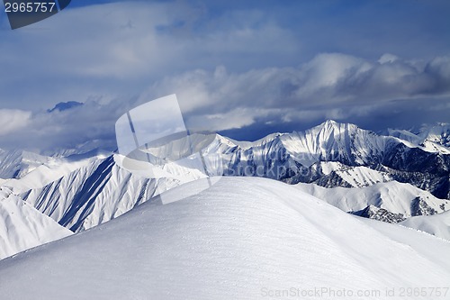 Image of Top of off-piste snowy slope and cloudy mountains