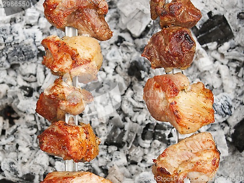 Image of Shish kebab on metal skewers over charcoal with ash