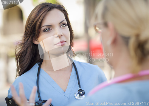 Image of Two Young Adult Female Doctors or Nurses Talking Outside