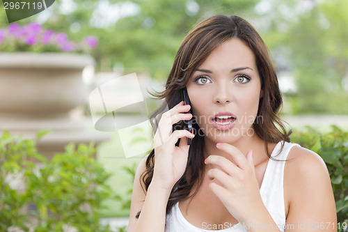 Image of Shocked Young Adult Female Talking on Cell Phone Outdoors