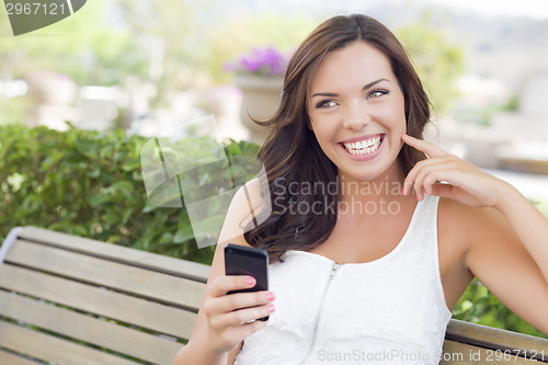 Image of Smiling Young Adult Female Texting on Cell Phone Outdoors