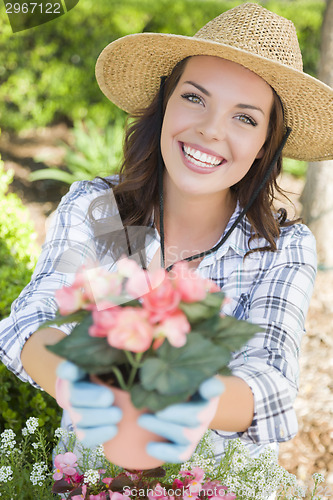 Image of Young Adult Woman Wearing Hat Gardening Outdoors