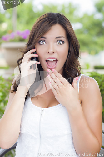 Image of Shocked Young Adult Female Talking on Cell Phone Outdoors