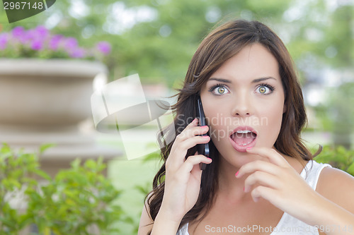 Image of Shocked Young Adult Female Talking on Cell Phone Outdoors