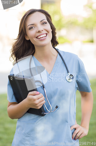 Image of Young Adult Woman Doctor or Nurse Holding Touch Pad Outside
