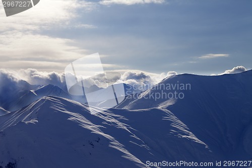 Image of Snowy mountains in mist at sun evening