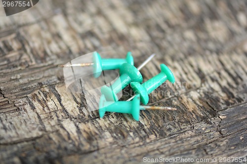 Image of green push pins on old wooden background