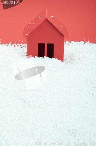 Image of paper house in snow on red background