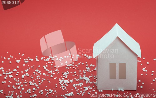 Image of paper house in snow on red background