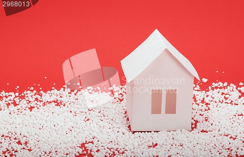 Image of paper house in snow on red background