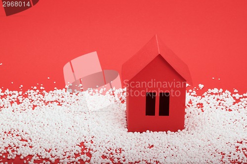 Image of paper house in snow on red background