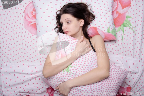 Image of Frightened young girl hugging a pillow while lying in bed