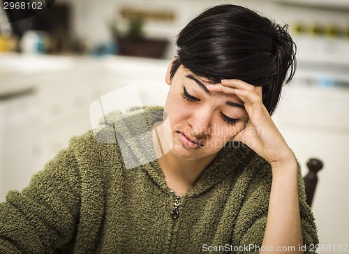 Image of Depressed Mixed Race Young Woman Sitting Alone In Kitchen