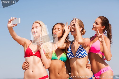 Image of group of smiling women making selfie on beach