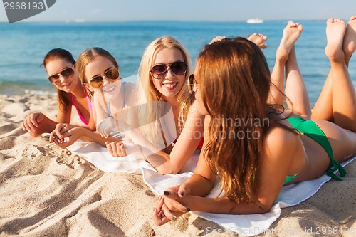 Image of group of smiling women in sunglasses on beach