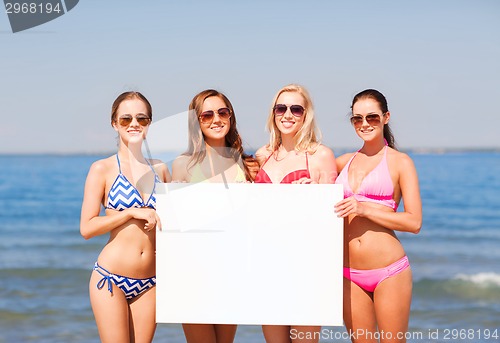 Image of group of smiling women with blank board on beach