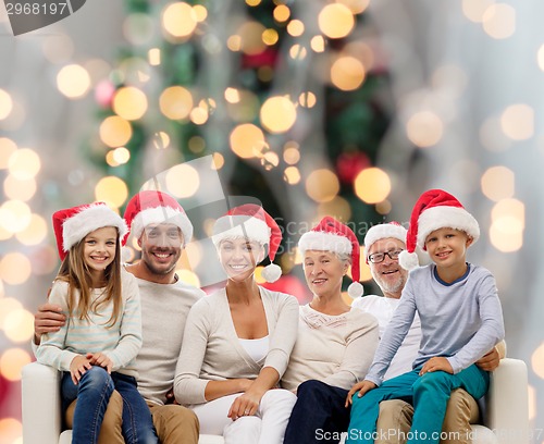 Image of happy family in santa helper hats sitting on couch