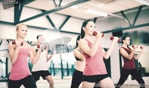 Image of group of smiling people working out with dumbbells