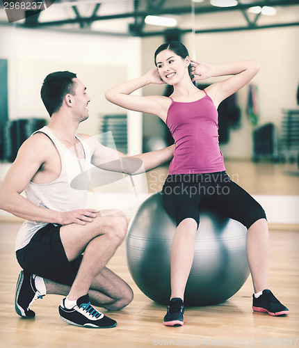 Image of male trainer with woman doing crunches on the ball