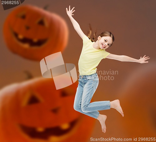 Image of smiling girl jumping over pumpkins background