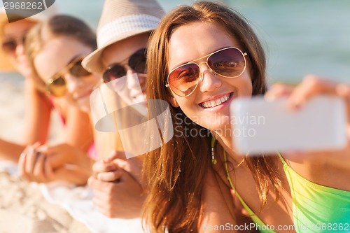 Image of close up of smiling women with smartphone on beach