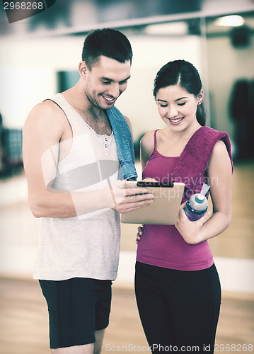 Image of two smiling people with tablet pc in the gym