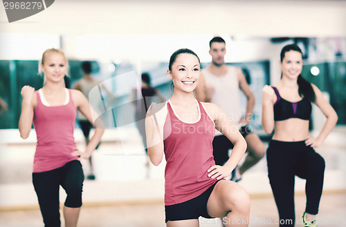 Image of group of smiling people exercising in the gym