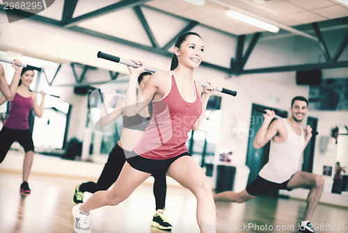 Image of group of smiling people working out with barbells