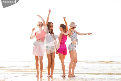 Image of group of smiling women dancing on beach