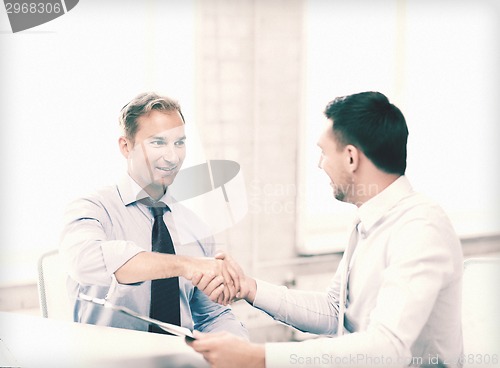 Image of businessmen shaking hands in office