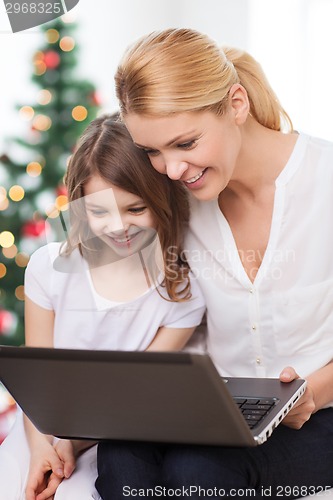 Image of smiling mother and little girl laptop computer