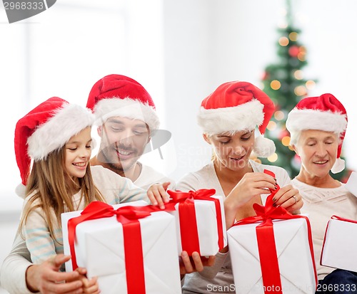 Image of happy family in santa helper hats with gift boxes