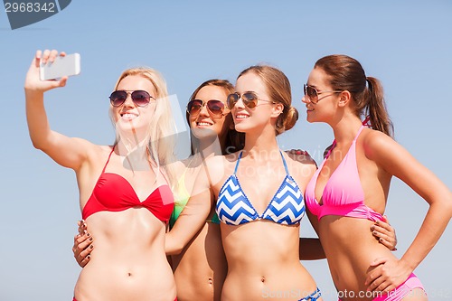 Image of group of smiling women making selfie on beach