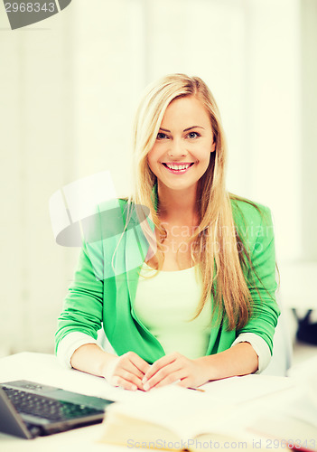Image of smiling student girl with laptop at school