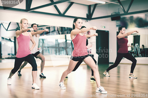 Image of group of smiling people exercising in the gym