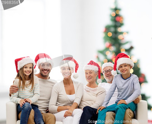 Image of happy family in santa helper hats sitting on couch