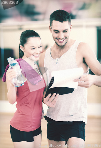 Image of smiling male trainer with woman in the gym