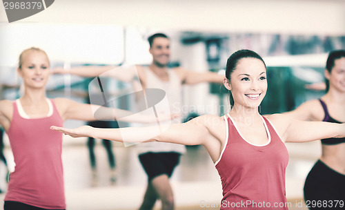 Image of group of smiling people exercising in the gym