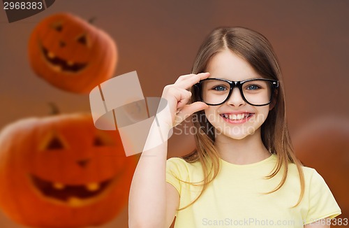 Image of smiling girl in glasses over pumpkins background