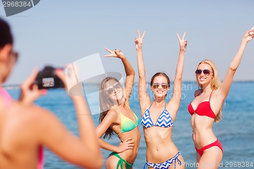 Image of group of smiling women photographing on beach