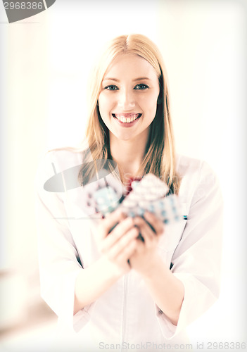 Image of young female doctor with pack of pills