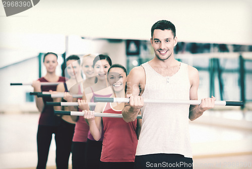 Image of group of smiling people working out with barbells