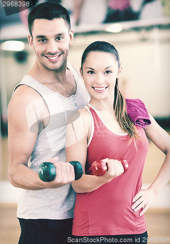 Image of two smiling people working out with dumbbells