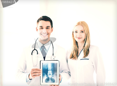 Image of two doctors showing x-ray on tablet pc