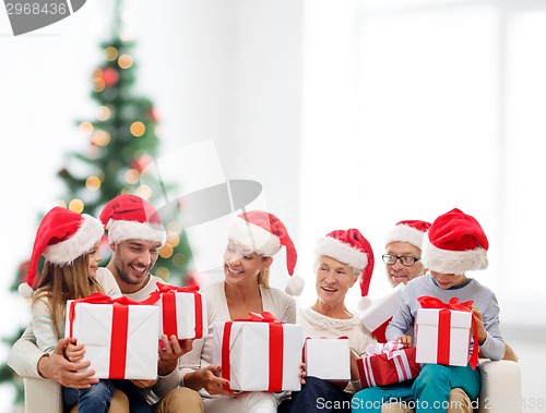 Image of happy family in santa helper hats with gift boxes