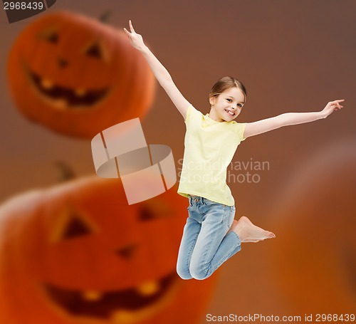 Image of smiling girl jumping over pumpkins background